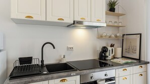 Una cucina moderna con mobili bianchi, un lavello nero, forno integrato e macchina per il caffè.