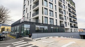 Un edificio moderno a più piani con balconi e ampie finestre, con un attraversamento pedonale di fronte.
