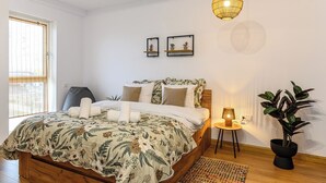 Una camera da letto con un letto, un comodino, una lampada e una pianta in vaso.