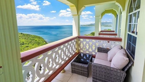 A balcony with wicker furniture and a view of the ocean. - 2BR Oceanview • Walk to Beach • Saint Lucia (Vieux Fort)
