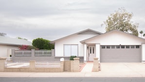 Une maison de plain-pied avec un garage, un porche à l’avant et une allée pavée en briques.