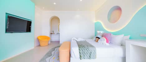 A modern bedroom with a bed, a small stool, a round rug, and a television mounted on the wall.