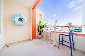 A balcony with a blue donut-shaped decoration, a potted plant, two pink chairs, and a blue chair. - Candy House Pool Villa with KTV (Pattaya)