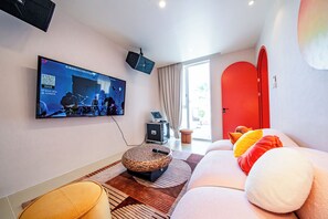 A modern living room with a flat-screen TV, a red door, and a sofa with cushions. - Candy House Pool Villa with KTV (Pattaya)