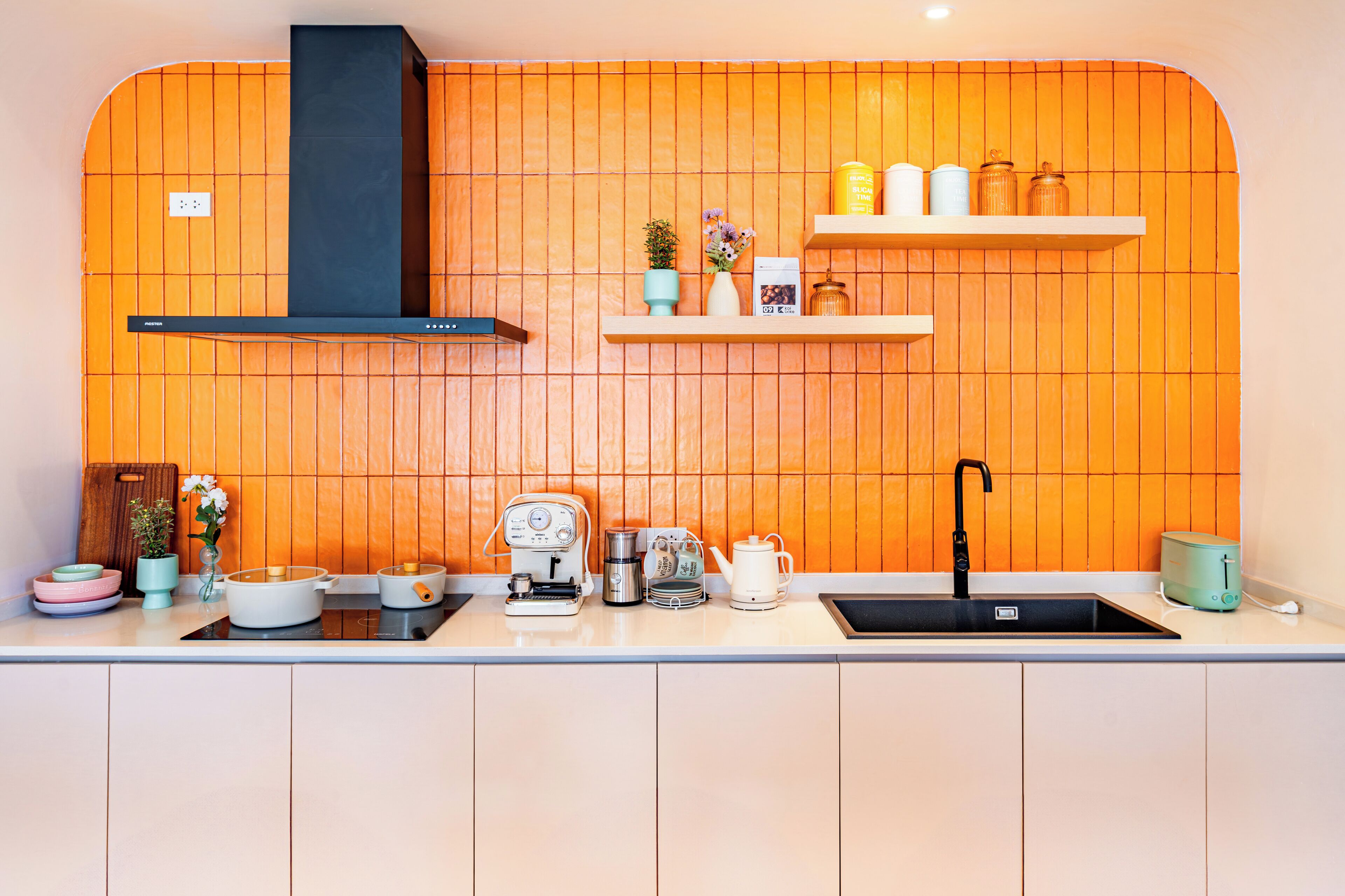 A kitchen with wooden paneling, a black range hood, a sink, and various appliances.