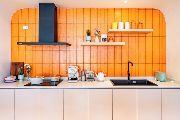 A kitchen with wooden paneling, a black range hood, a sink, and various appliances. - Candy House Pool Villa with KTV (Pattaya)