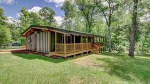 A wooden cabin with a porch, surrounded by trees.