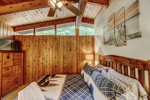A wooden cabin bedroom with a bed, dresser, and ceiling fan. - Is today a Lake or Links kind of day? Now booking for Summer 2026! (Breezy Point)
