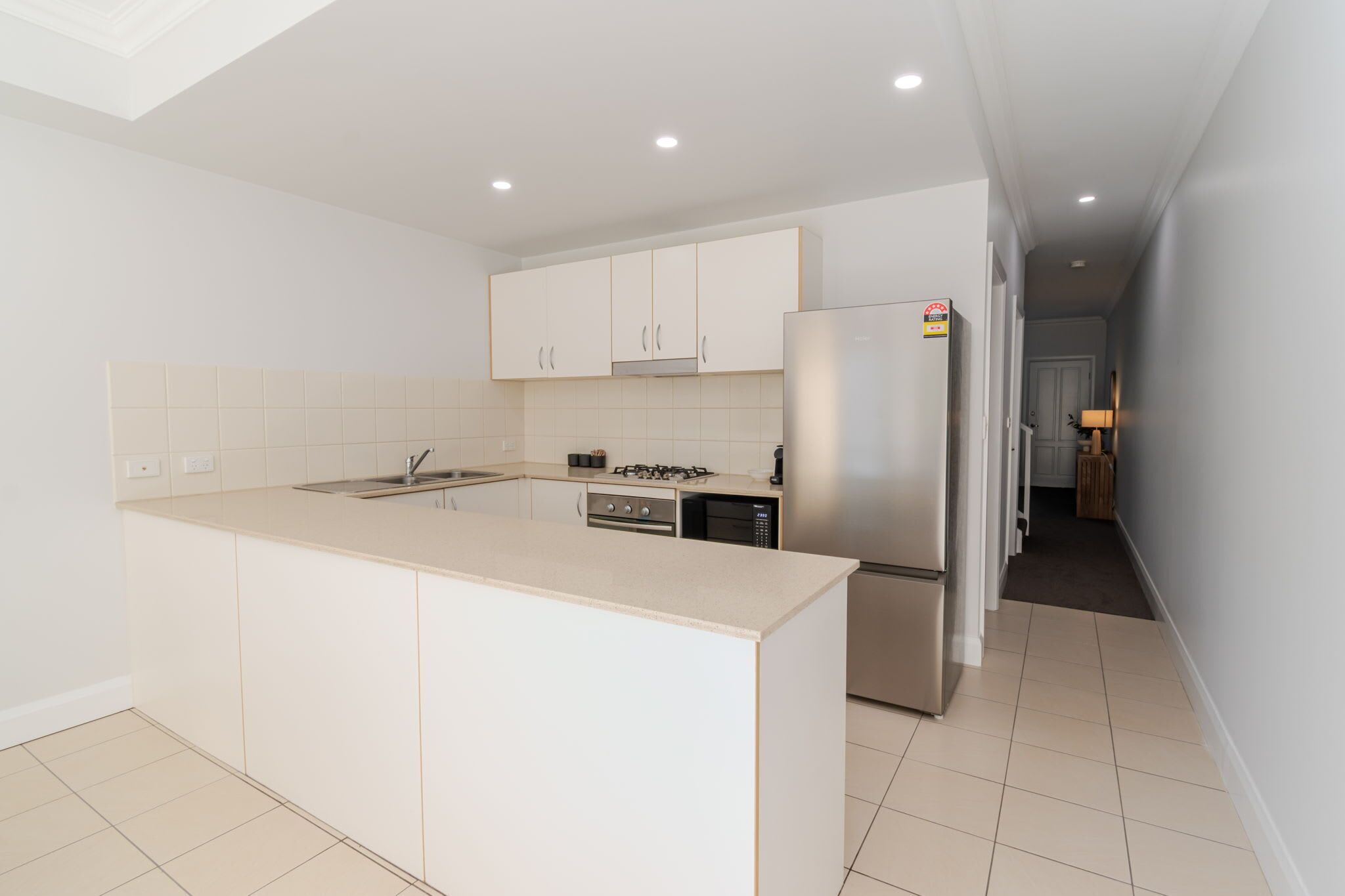 A modern kitchen with white cabinets, a stainless steel refrigerator, and a central island.