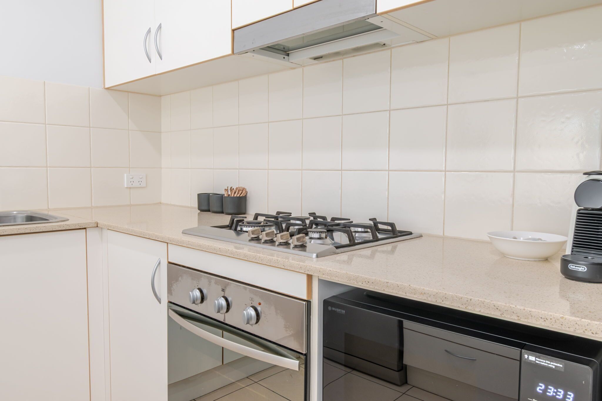 Une cuisine moderne avec des meubles blancs, une cuisinière à gaz, un four et un lave-vaisselle.