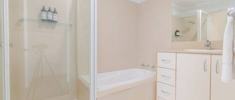 A modern bathroom with a glass-enclosed shower, a freestanding bathtub, and a vanity with a mirror.