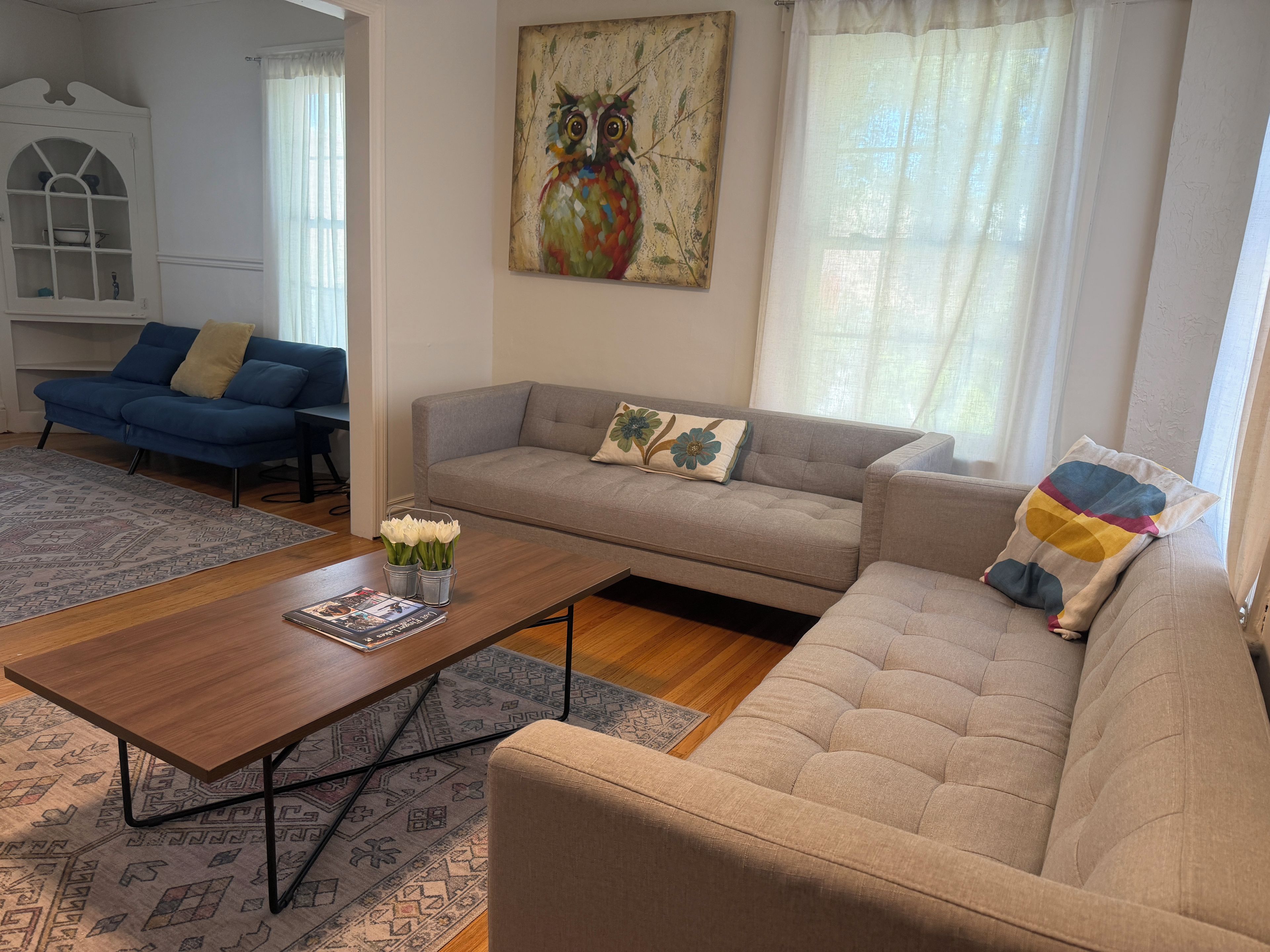Un salon avec un canapé, une table basse et un tableau accroché au mur.