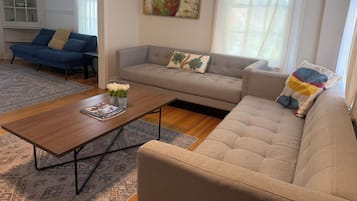 A living room with a sofa, a coffee table, and a painting on the wall.