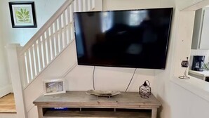 A living room with a mounted flat-screen TV, a wooden entertainment center, and a staircase.