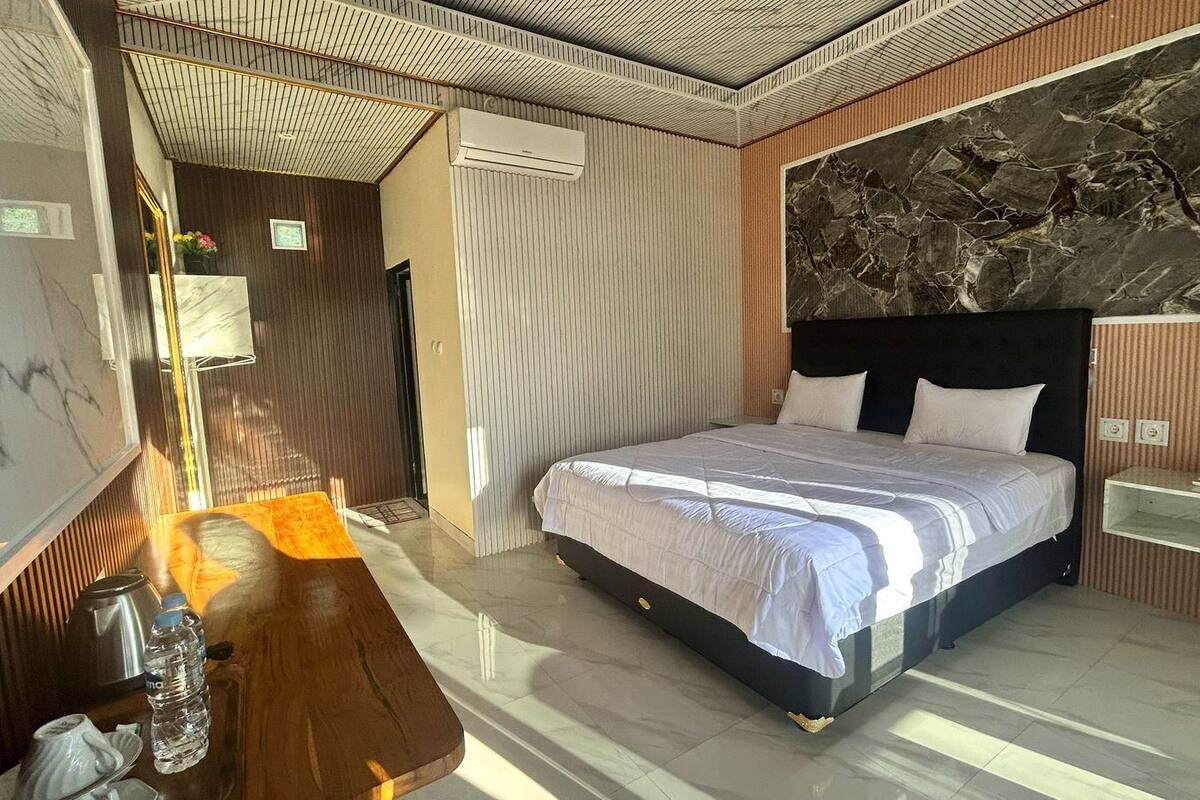 A modern bedroom with a large bed, a wooden side table, a marble wall, and a built-in shelf.