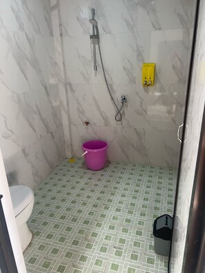 A small bathroom with a toilet, a shower, and a bucket. - Hotel Villa Beach Transit 2 (Labuan Jambu)