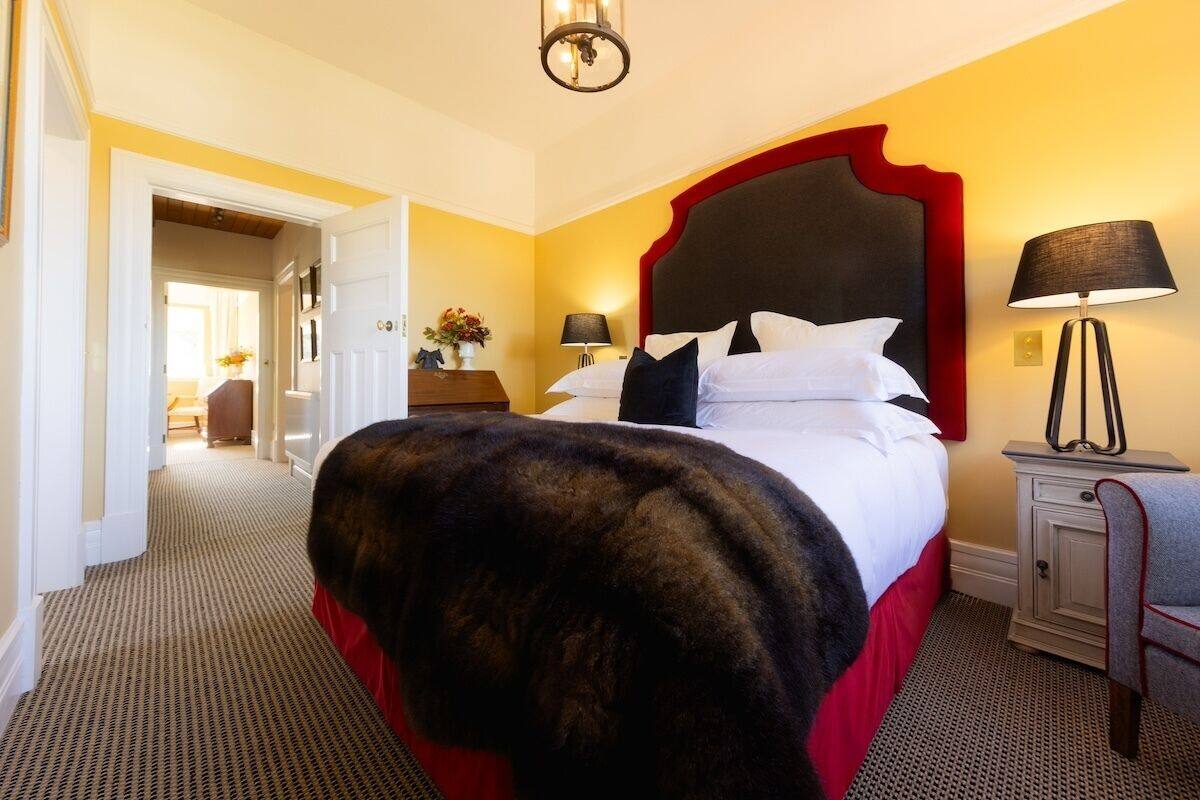A hotel room with a large bed, a nightstand, a lamp, and a chair.