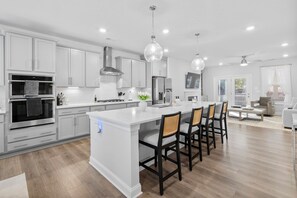 A modern kitchen with white cabinetry, stainless steel appliances, and a central island with bar stools.