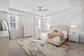A bedroom with a bed, nightstands, a dresser, and a ceiling fan.