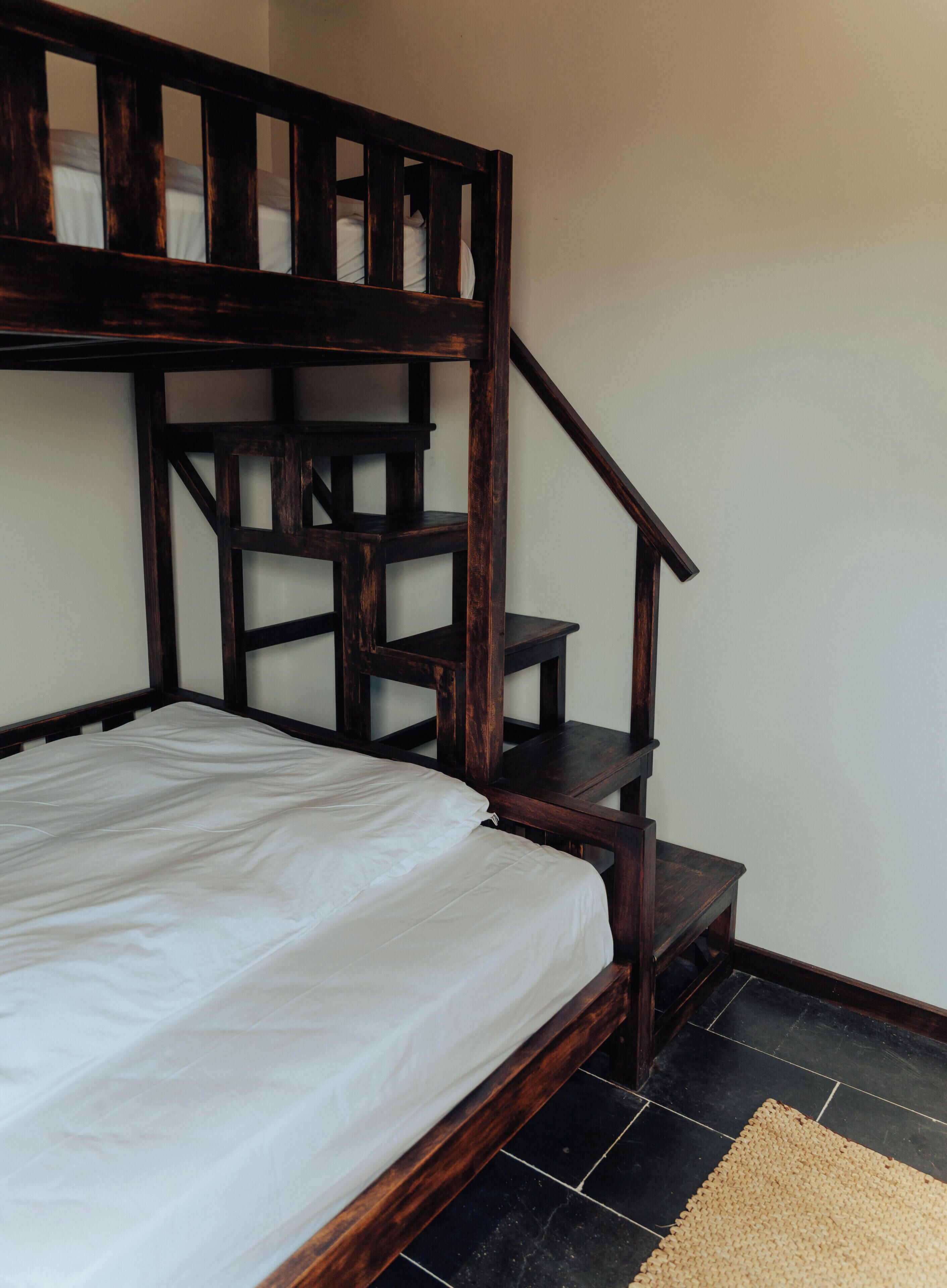A bunk bed with a wooden headboard and a staircase leading to an upper bunk.