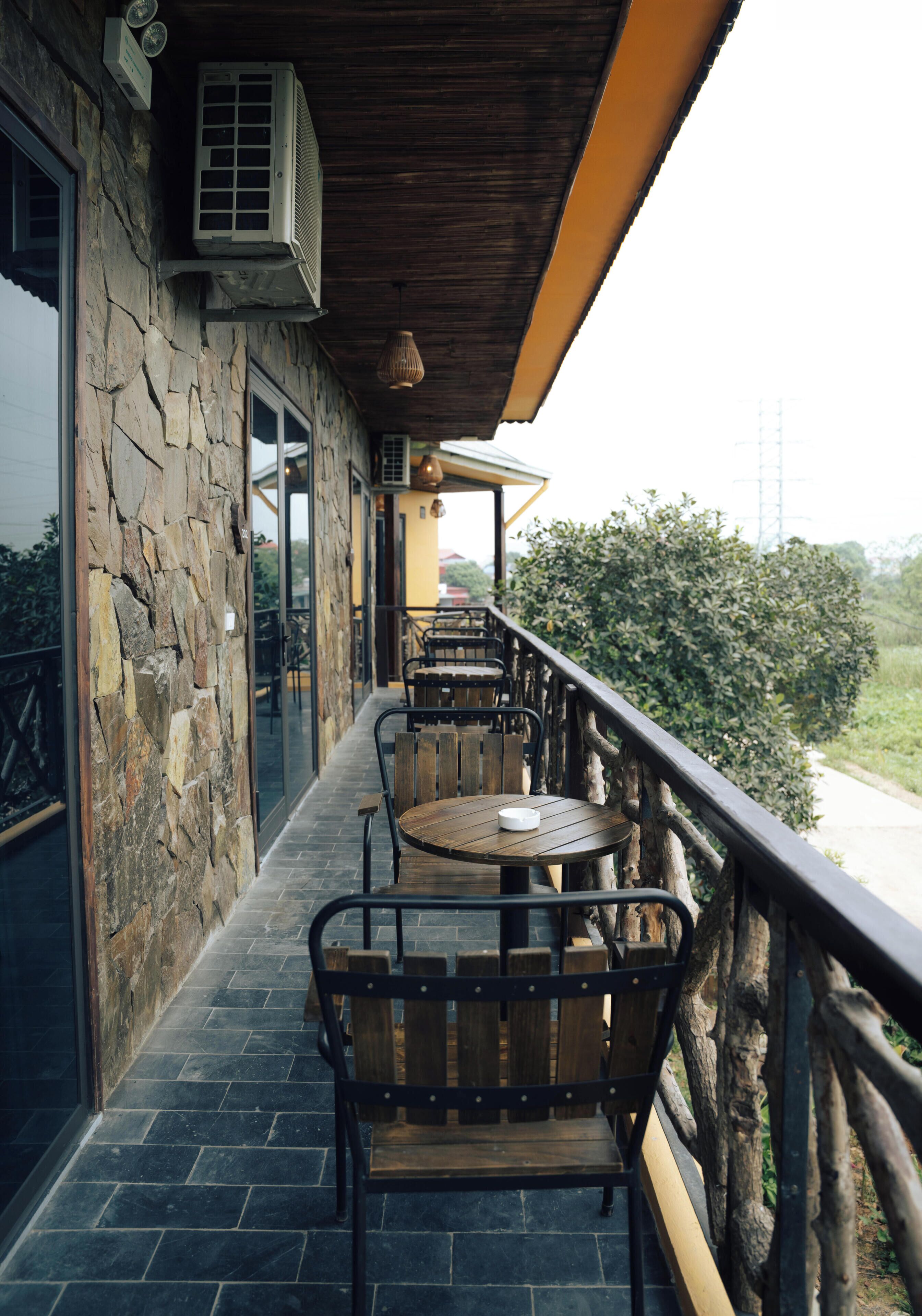 A balcony with stone walls, a wooden table, and chairs.