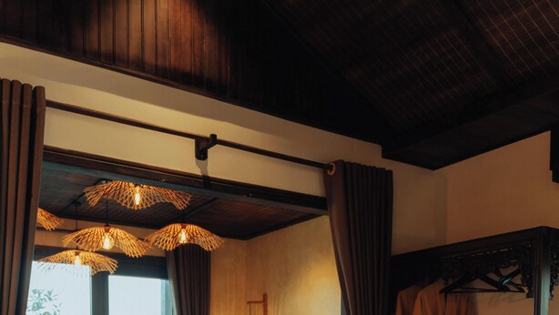 A bedroom with a large bed, a bathtub, a vanity with a mirror, and a window with curtains. - Ninh Binh Rustic Hideaway (Nam Hoa Lu)