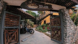 A rustic hideaway entrance with wooden gates, a stone wall, and a motorcycle parked outside. - Ninh Binh Rustic Hideaway (Nam Hoa Lu)