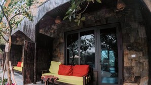 A rustic hideaway with a stone exterior, a wooden bench with cushions, and a glass door entrance. - Ninh Binh Rustic Hideaway (Nam Hoa Lu)