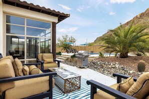 An outdoor patio with beige sofas, a metal coffee table, and a barbecue grill. - Falling Star by LuxeKey: Southwest Charm w/ Mountain Views & Pool (Phoenix)