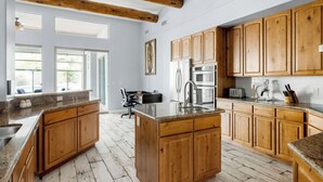 Een keuken met houten kastjes, granieten aanrechtbladen en een groot eiland.