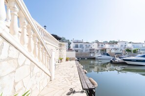 A stone staircase leading to a balcony overlooking a marina with boats docked. - Los Amigos Goertz house, 15m mooring and swimming pool (Empuriabrava)
