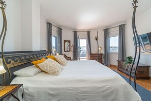 Een slaapkamer met een groot bed, een dressoir, een spiegel en een televisie.