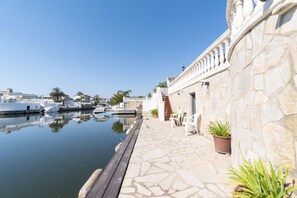 A stone building with a pool, potted plants, and a clear sky. - Los Amigos Goertz house, 15m mooring and swimming pool (Empuriabrava)