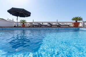 A clear blue pool with lounge chairs and umbrellas, a white fence, and potted plants. - Los Amigos Goertz house, 15m mooring and swimming pool (Empuriabrava)