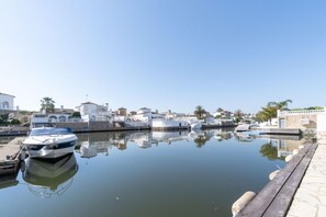 A marina with boats docked, calm water, and buildings with white walls and red roofs. - Los Amigos Goertz house, 15m mooring and swimming pool (Empuriabrava)