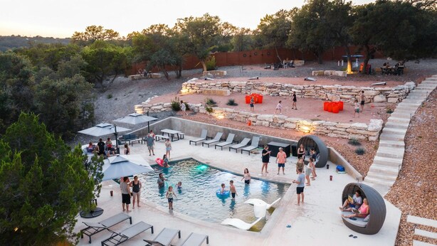 An outdoor swimming pool area with lounge chairs, a hot tub, and a stone fire pit. - Starlight Horizon 4 Cabins (3 Bed Each) Pool, Firepits, Sleeps up to 32 (Canyon Lake)