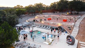 An outdoor swimming pool area with lounge chairs, a hot tub, and a stone fire pit. - Starlight Horizon 2 Cabins + Hot Tub, Pool, Firepits, Sleeps up to 11 (Canyon Lake)