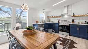 A modern kitchen with white subway tiles, blue cabinets, and stainless steel appliances. - Starlight Horizon 3 Cabins + Hot Tub, Pool, Firepits, Sleeps up to 19 (Canyon Lake)