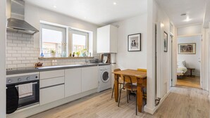 Eine moderne Küche mit Einbauofen, Waschmaschine und Essbereich mit Holztisch und Stühlen.