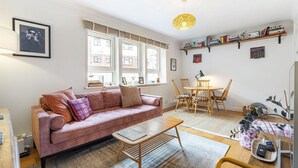 Ein Wohnzimmer mit einer Couch, einem Couchtisch, einem Esstisch, Stühlen und einem Bücherregal.