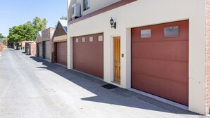 A row of buildings with garage doors, a clear sky, and trees in the background. - Hidden Gem - Fremantle Apartment (Fremantle)