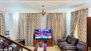 Ein Wohnzimmer mit Fernseher, Ledersofas, einem Couchtisch und einer Treppe.