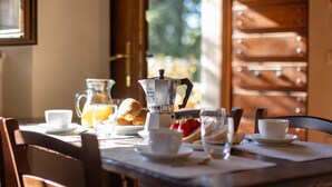 Une table de petit-déjeuner avec une machine à café, des croissants et une carafe de jus d’orange.