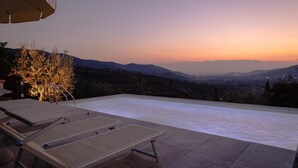 Une piscine à débordement offrant une vue sur les montagnes lointaines au coucher du soleil.