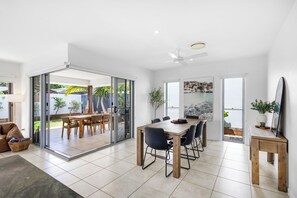 A spacious dining area with a large table and chairs, a ceiling fan, and a view of the outdoors through glass doors. - Mooloolaba Parkway Palms Retreat | Spacious 3BR with Patio & BBQ | Pet-Friendly (Mooloolaba)
