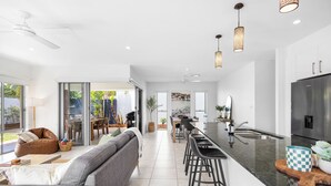 A modern kitchen with a central island, bar stools, and a stainless steel refrigerator. - Mooloolaba Parkway Palms Retreat | Spacious 3BR with Patio & BBQ | Pet-Friendly (Mooloolaba)