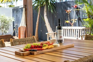 A wooden table with a cheese board, grapes, strawberries, and a bottle of wine. - Mooloolaba Parkway Palms Retreat | Spacious 3BR with Patio & BBQ | Pet-Friendly (Mooloolaba)