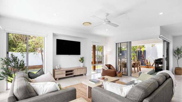 A modern living room with a flat-screen TV, grey sofas, a wooden coffee table, and a ceiling fan. - Mooloolaba Parkway Palms Retreat | Spacious 3BR with Patio & BBQ | Pet-Friendly (Mooloolaba)