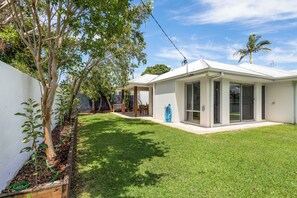 A modern house with a well-maintained lawn, a wooden deck, and a clear sky. - Mooloolaba Parkway Palms Retreat | Spacious 3BR with Patio & BBQ | Pet-Friendly (Mooloolaba)