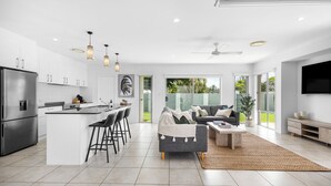 A modern kitchen with a central island, bar stools, and a dining area. - Mooloolaba Parkway Palms Retreat | Spacious 3BR with Patio & BBQ | Pet-Friendly (Mooloolaba)